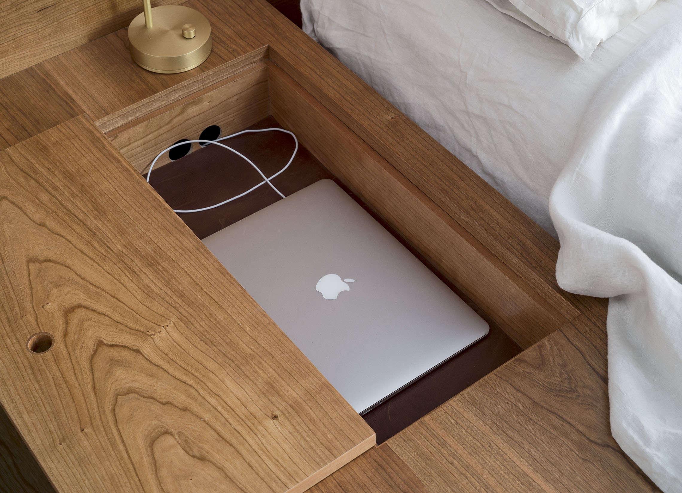 A custom platform bed tricked out with a compartment for devices. Photograph by Matthew Williams, courtesy of Workstead, from The Craftsman-Made NYC Apartment, Workstead Edition.