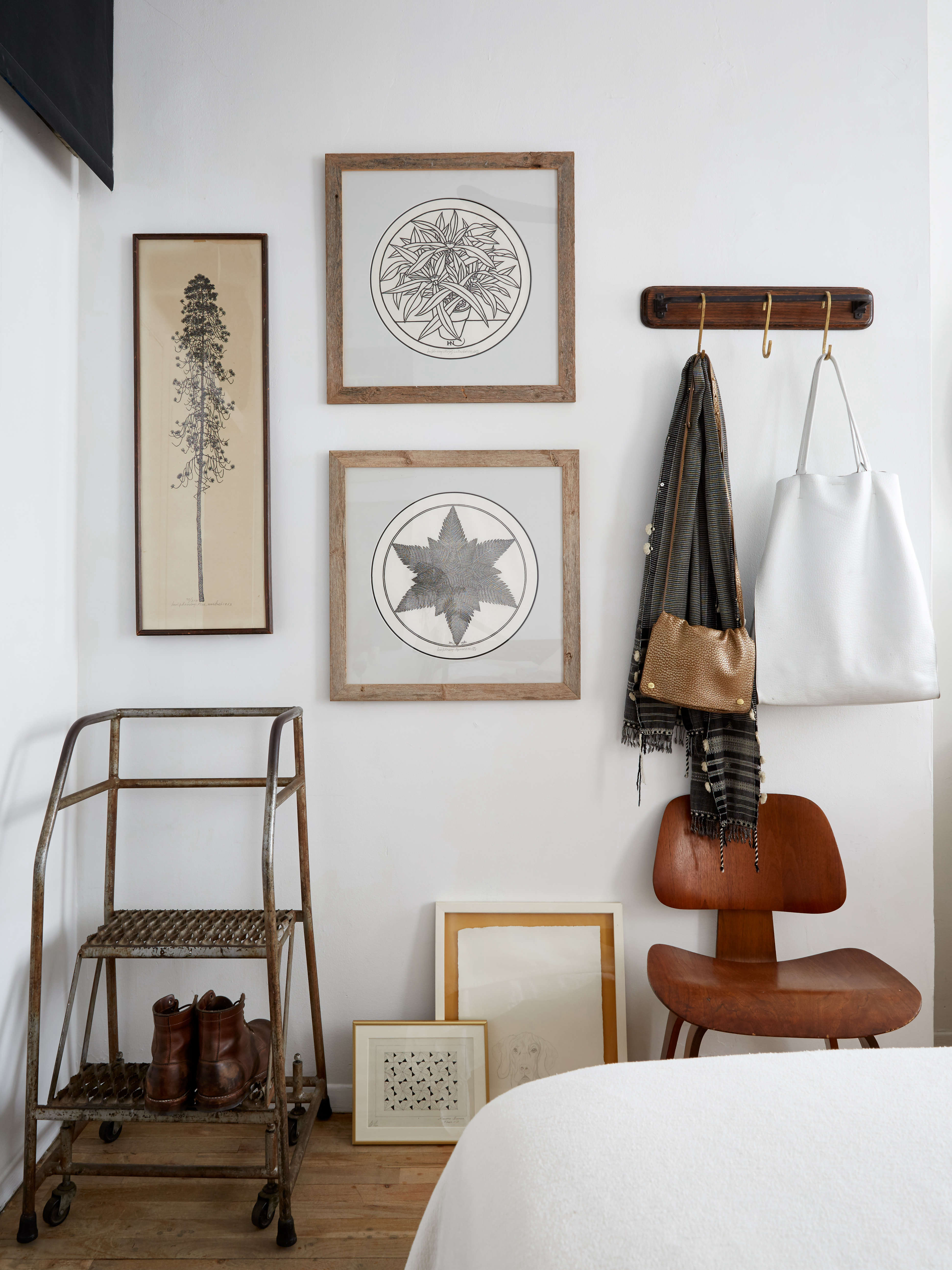 Framed black and white prints and an industrial step stool on wheels in an artful apartment bedroom