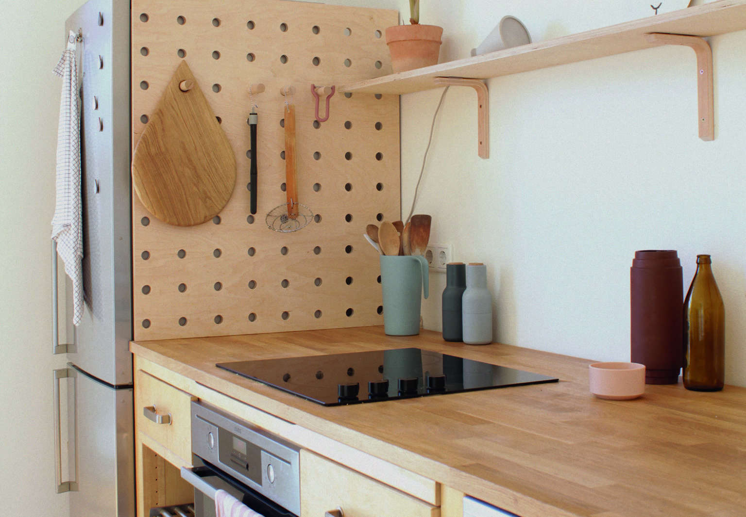 A DIY wooden pegboard in the kitchen of illustrator/graphic designer Swantje Hindrichsen created from used Ikea components.