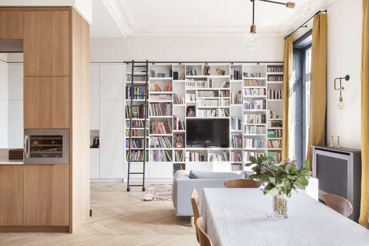 Architect Camille Hermand designed a full-height bookcase lacquered in Farrow & Ball Strong White for this family room. It has a custom black metal sliding ladder and storage cabinets that wrap around the wall. See In Paris, a Grand Apartment Gets an Update for a Modern Family. Photograph by Hervé Goluza.